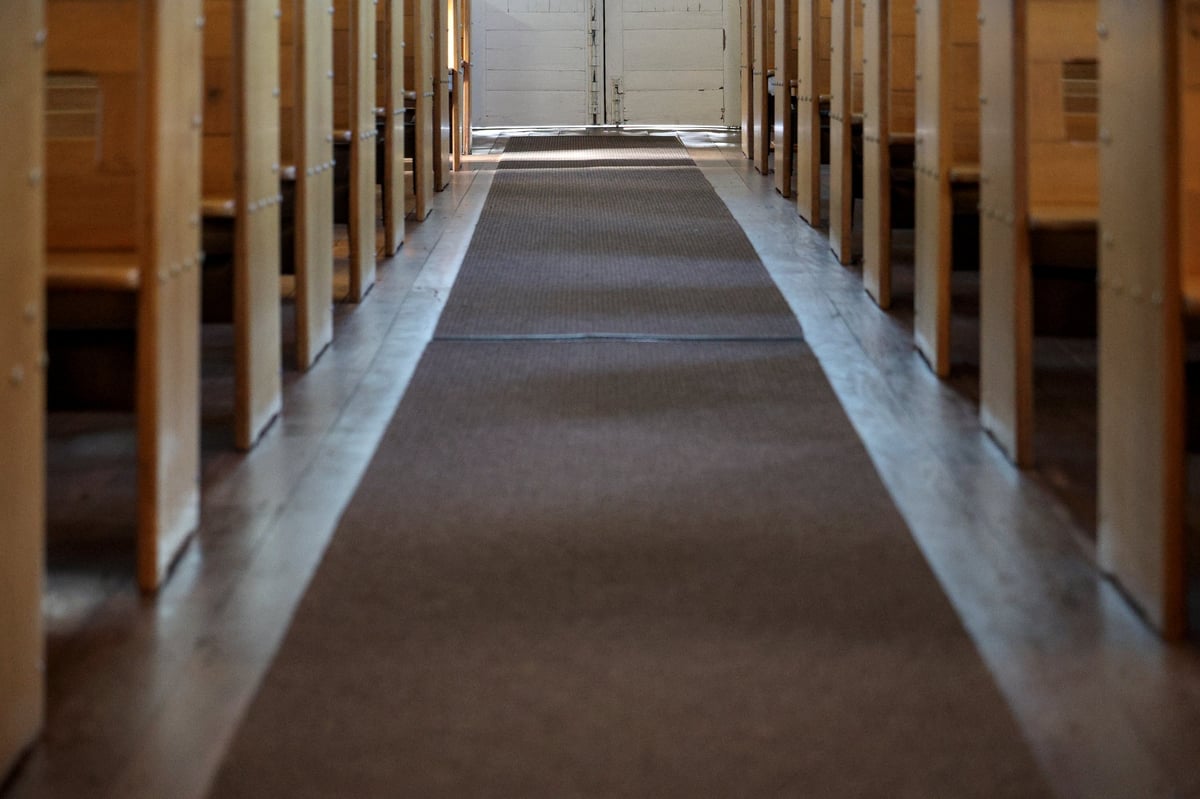 A quiet traditional church interior with wooden pews and an aisle leading toward the entrance